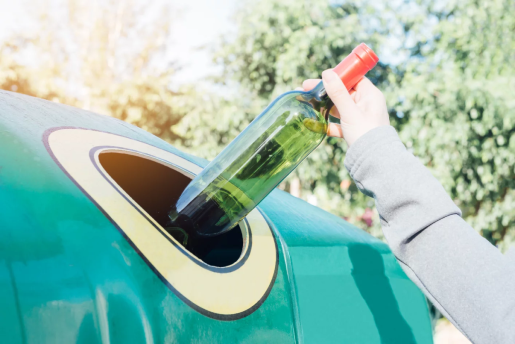 Persona reciclando vidrio en un iglú verde